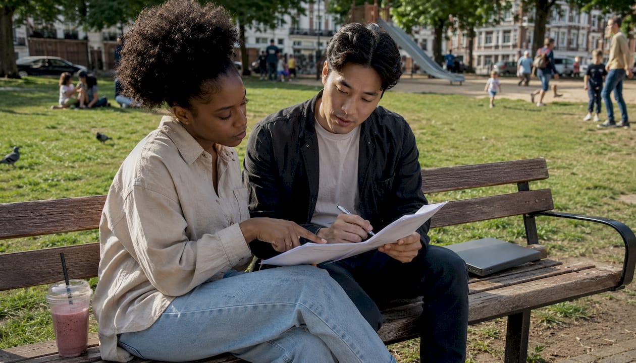 Twee influencers zitten samen om tafel om hun contract en verzekeringen door te nemen.